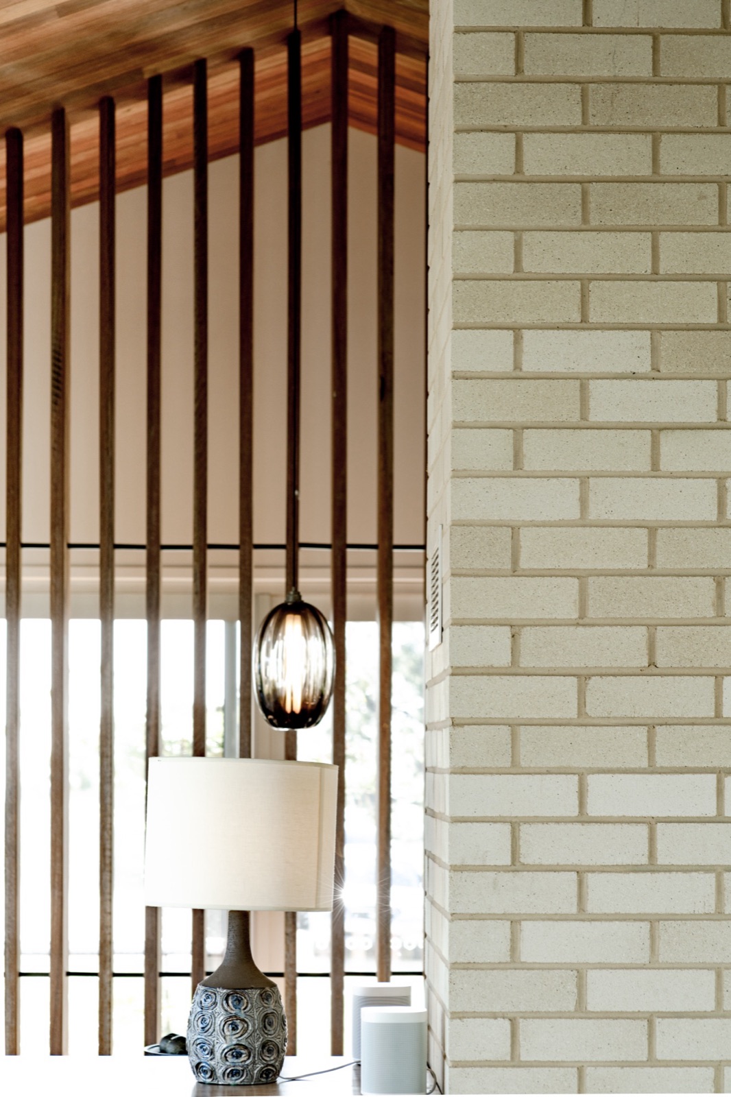 Interior of a high performance home: timber screen, cream brick fireplace and spotted gum ceiling